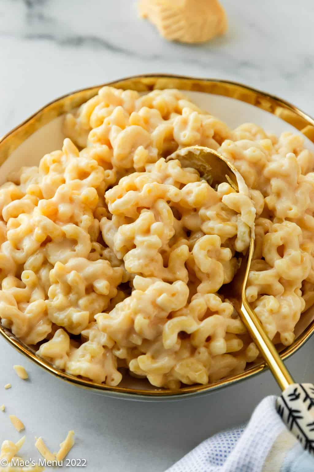 Taking a scoop of mac and cheese in a bowl.