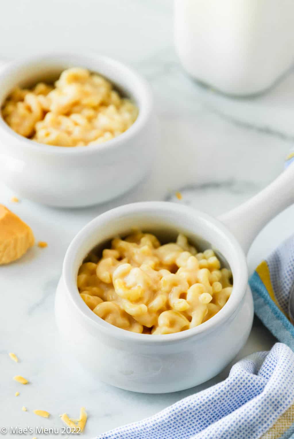 Two small bowl of smoked gouda mac and cheese in front of a bottle of milk.
