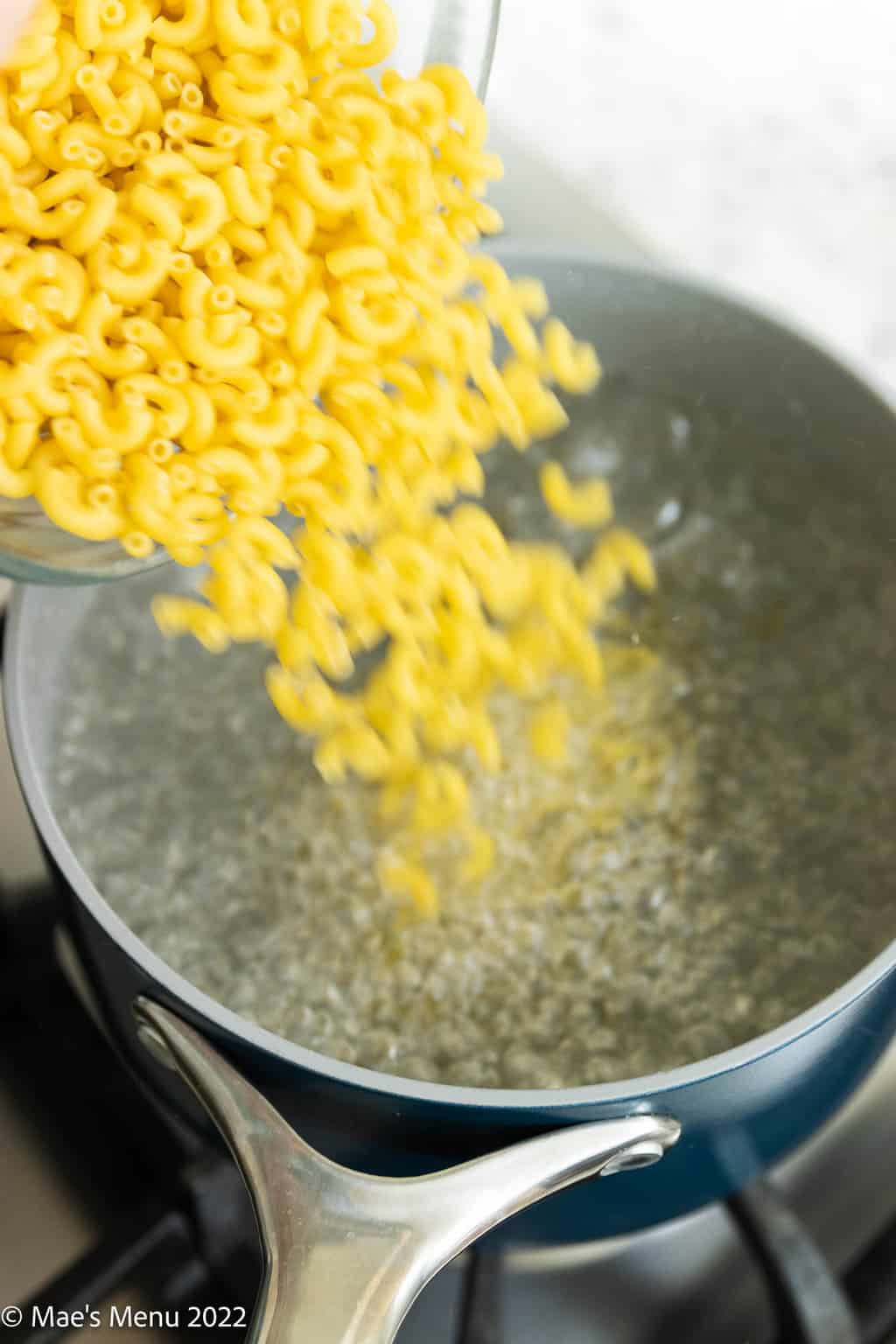 Pouring macaroni into a pot of boiling water.