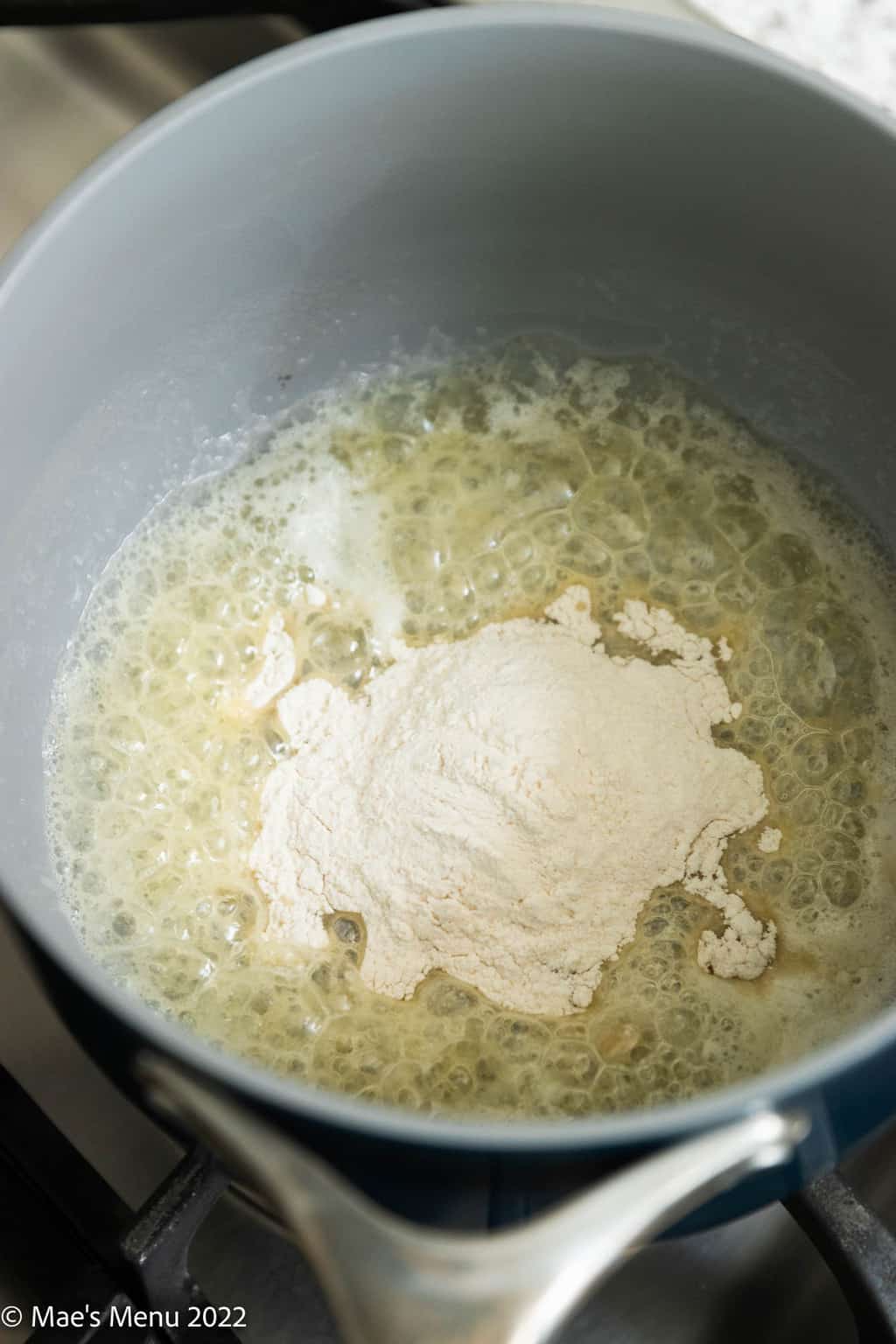 An overhead shot of a sauce pan with butter and flour.