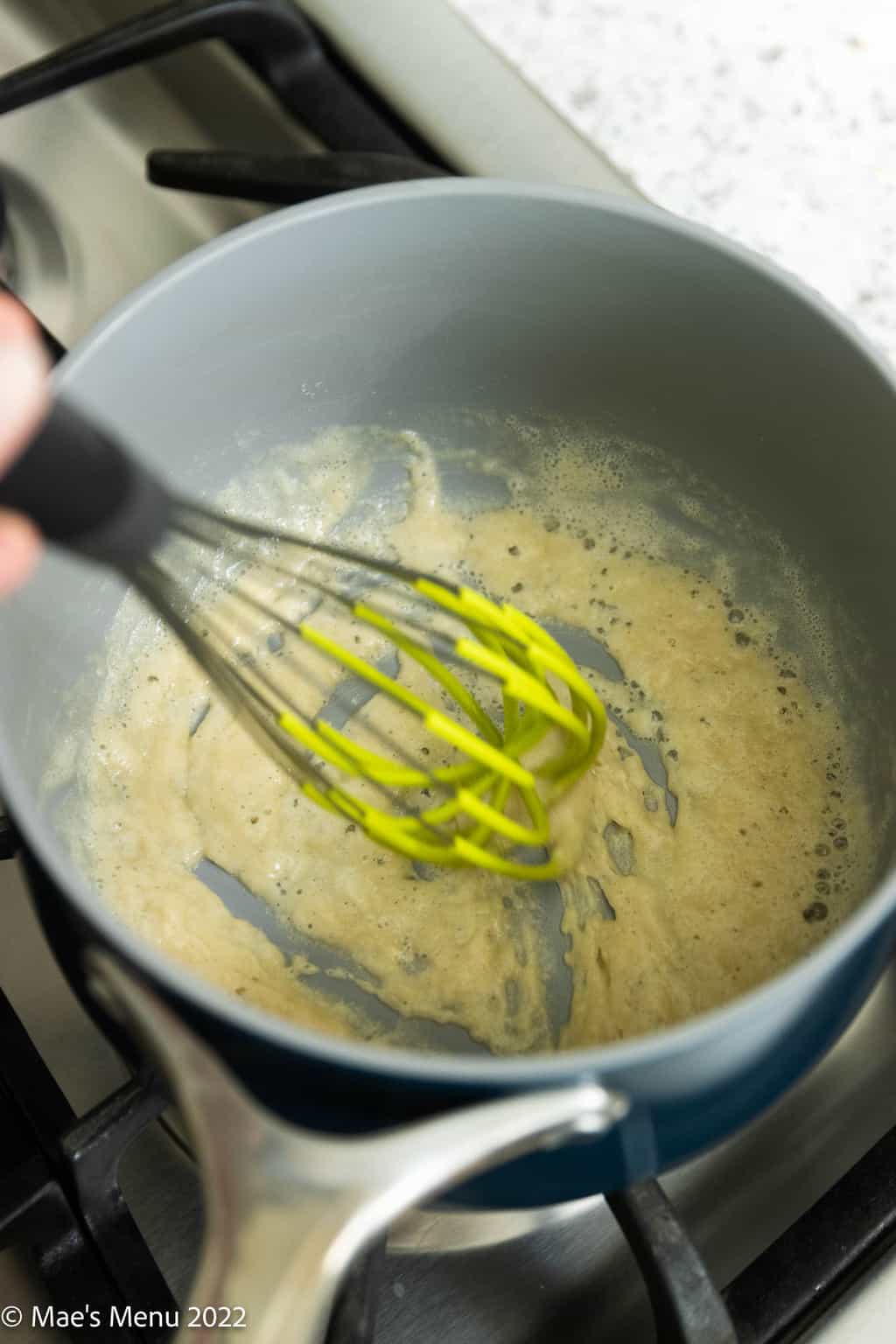Whisking butter and flour in a saucepan.