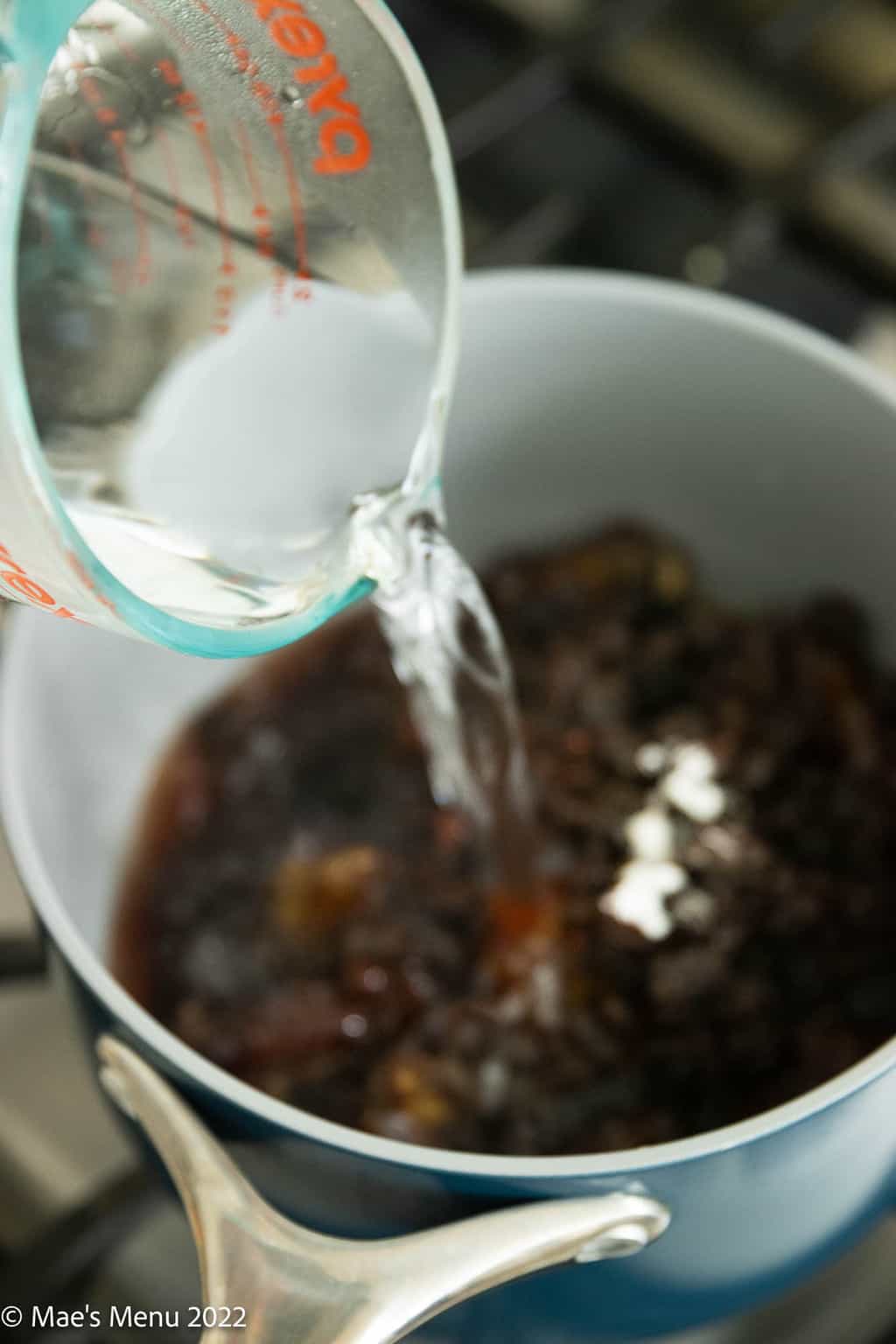 Pouring hot water into a small saucepan with dates and raisins.