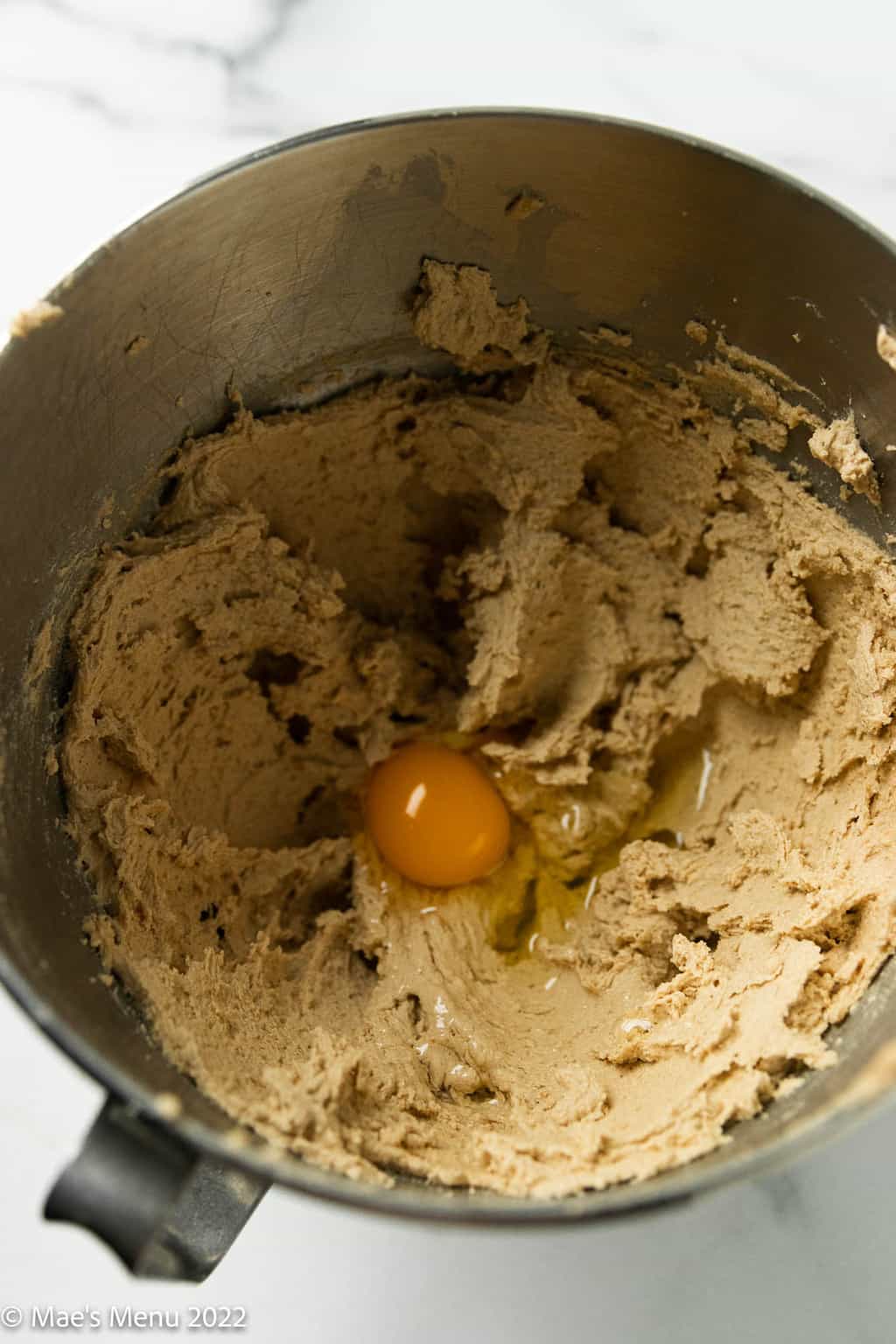A mixing bowl with creamed brown sugar and butter with an egg added.