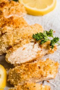 An up-close shot of a sliced panko chicken breast with parlsey.