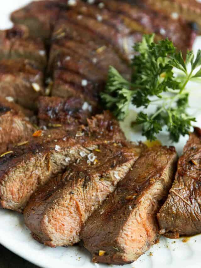 An up-close shot of sliced flat iron steak on a white plate.