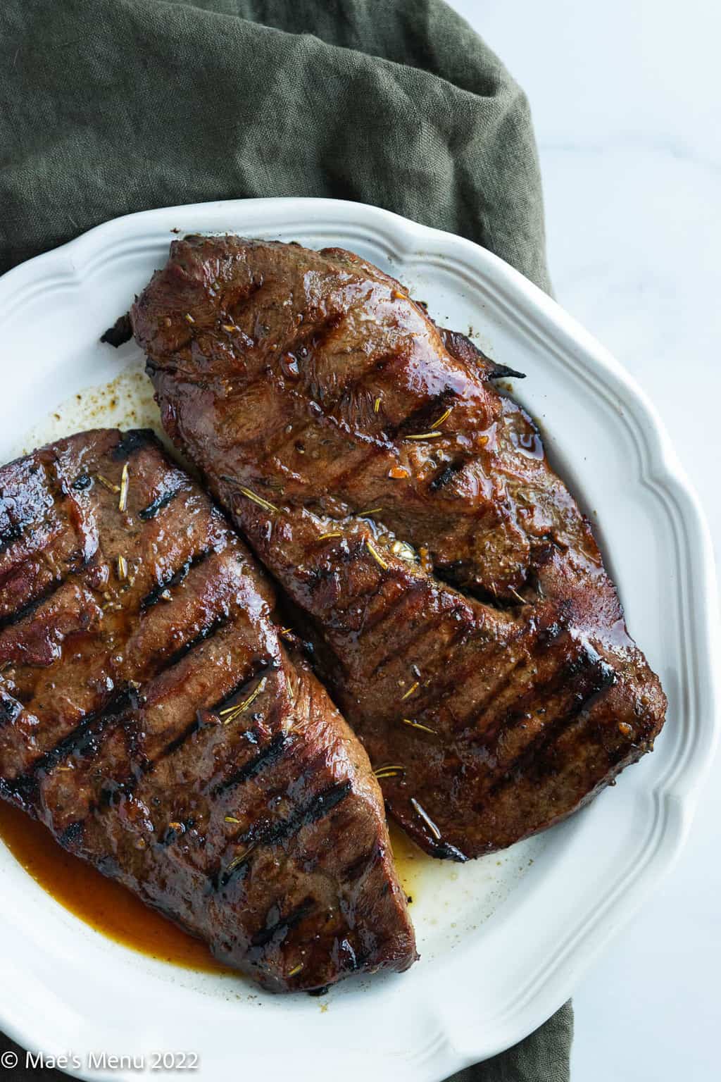 Two pieces of grilled flat iron steak on a white serving plate.