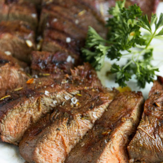 An up-close shot of sliced flat iron steak on a white plate.