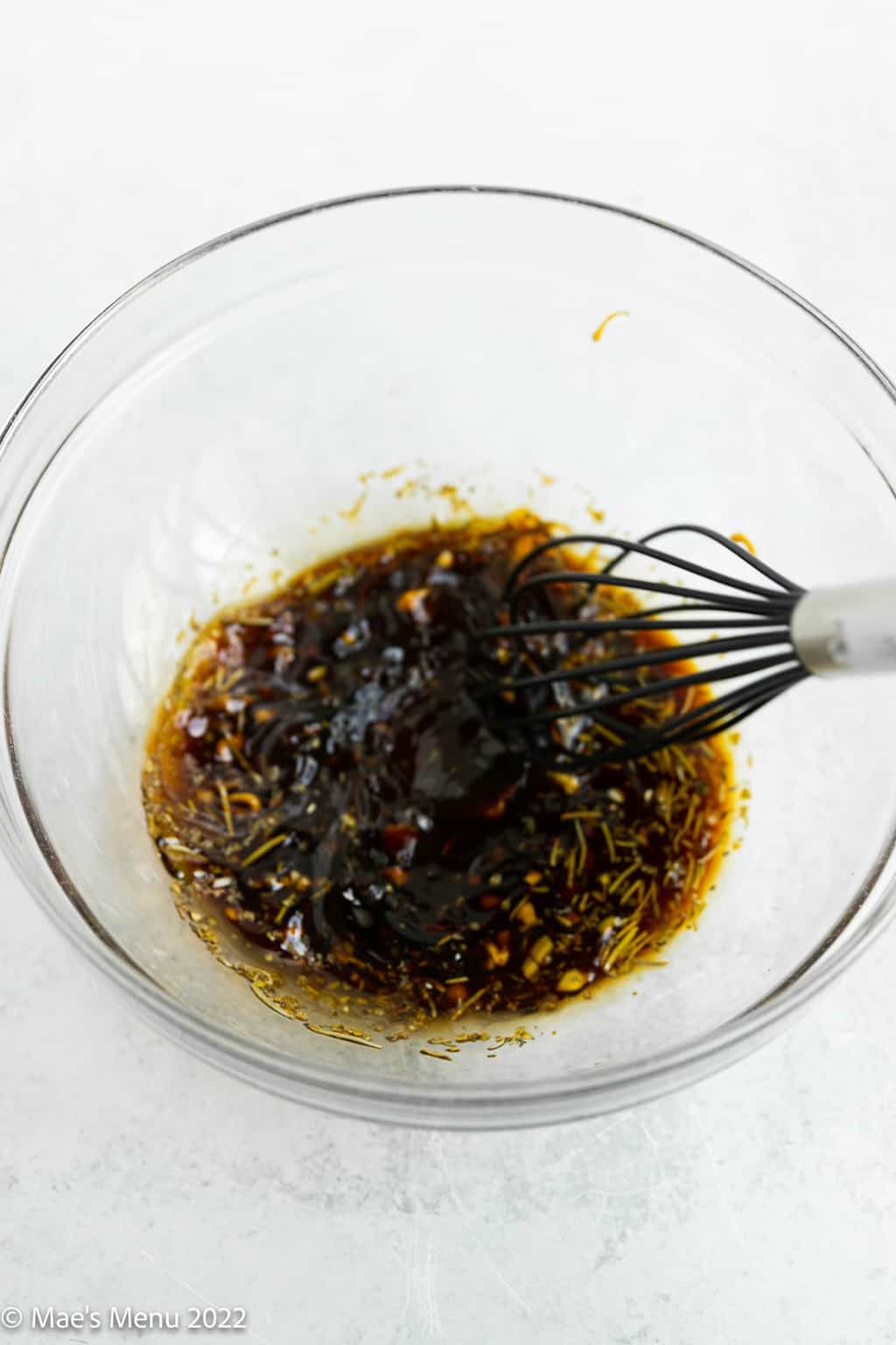 Whisking the steak marinade in a clear bowl.