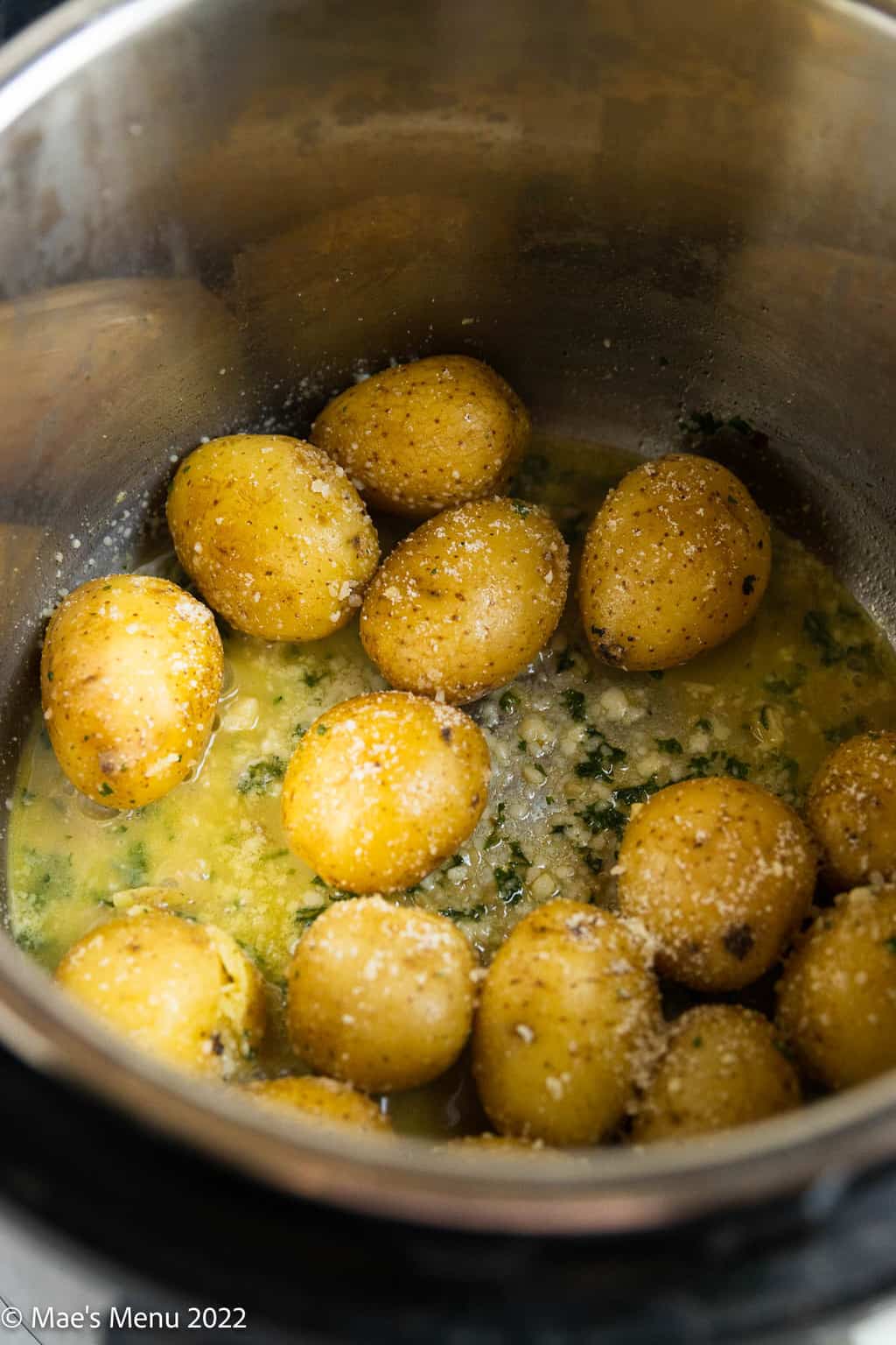 An over head shot of an Instant pot with baby potatoes sprinkled with parmesan cheese.