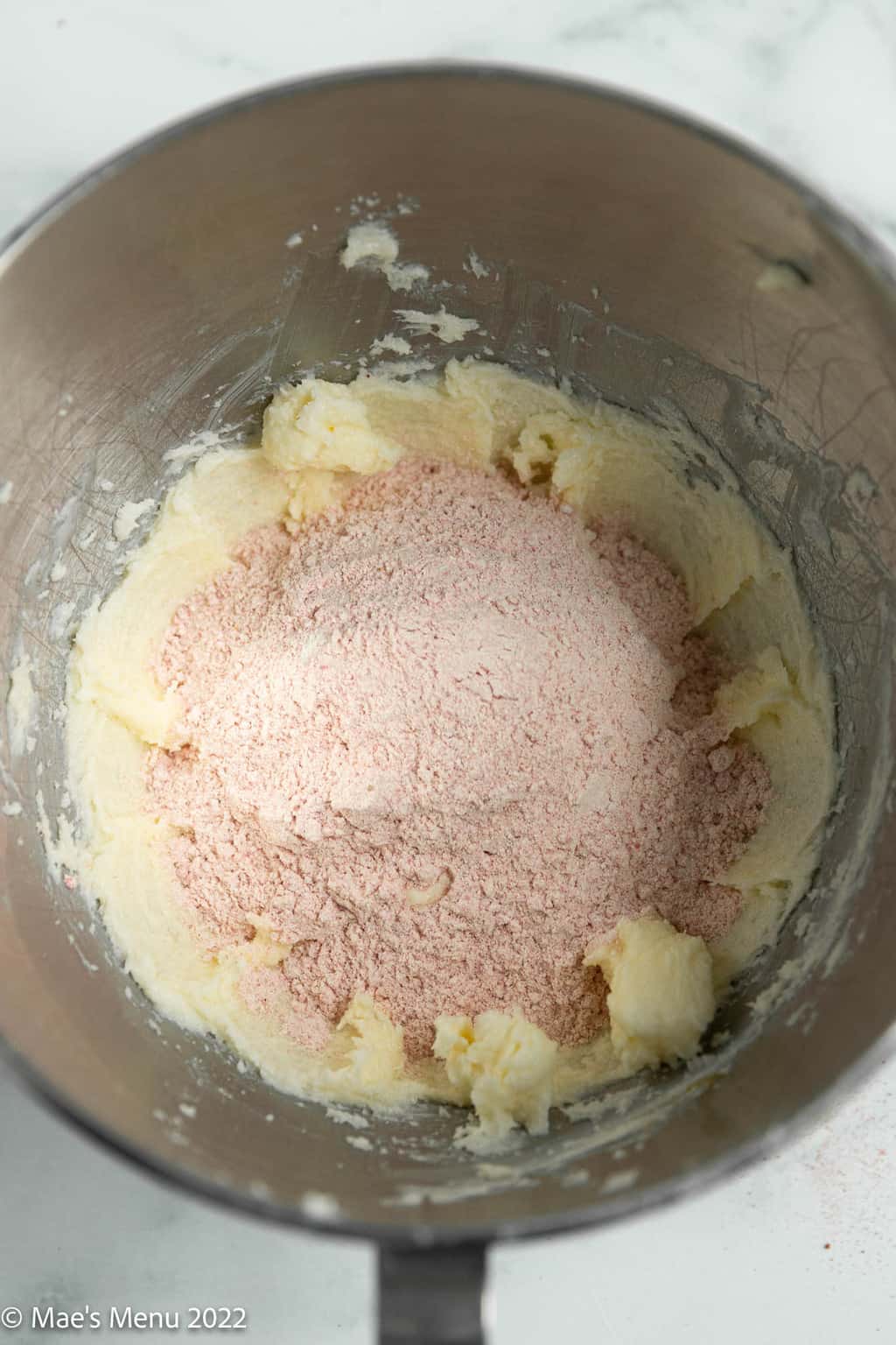 Creamed butter and strawberry flour mix in a mixing bowl.