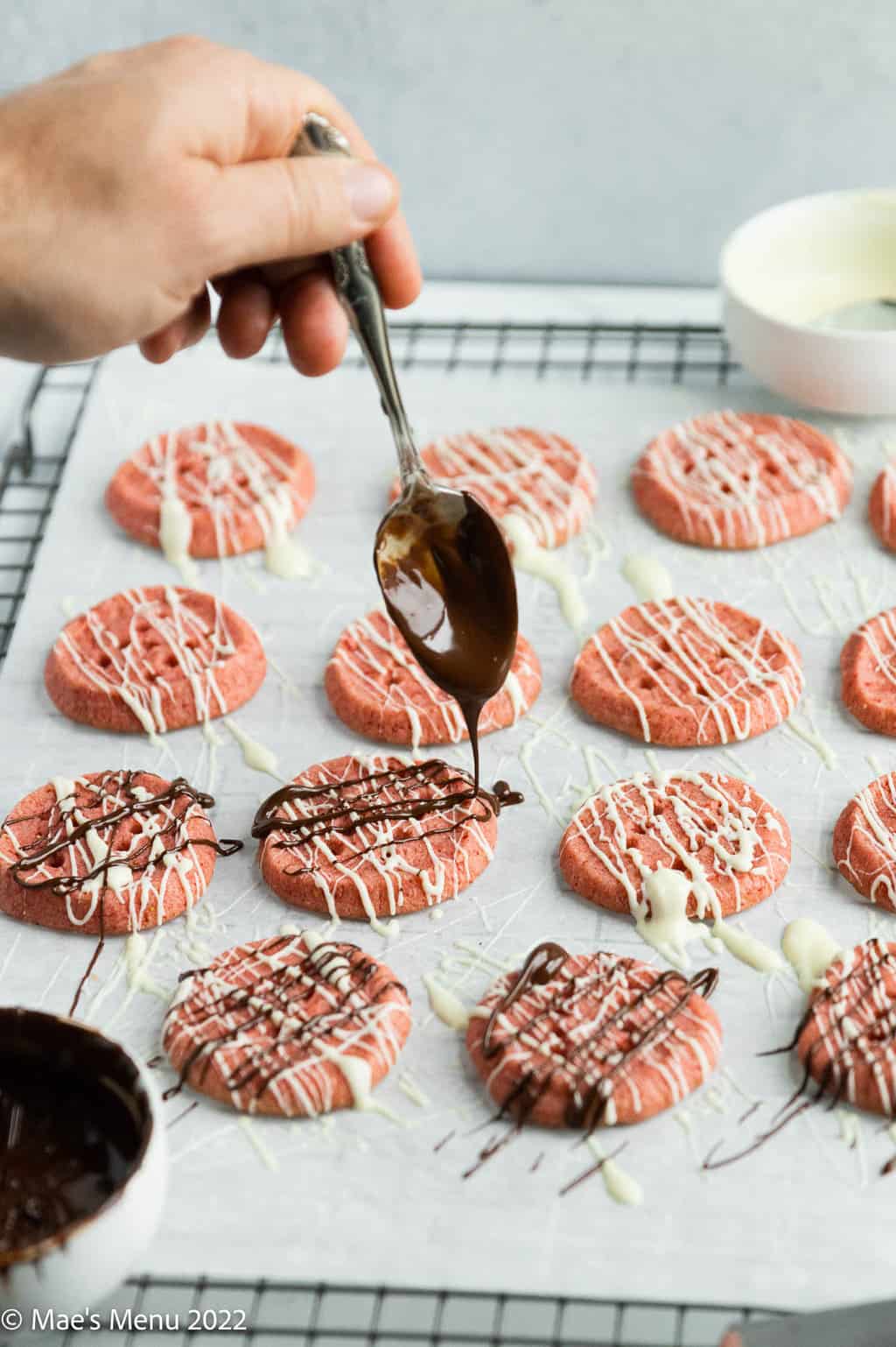 Drizzling melted chocolate over the strawberry cookies.