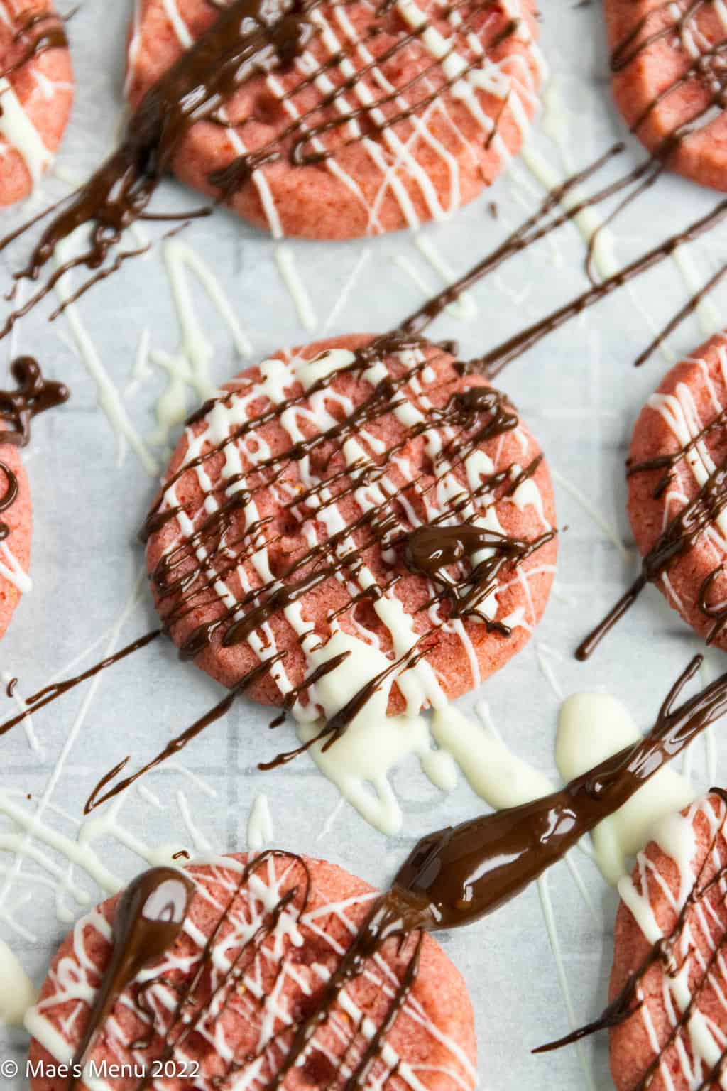 An up-close shot of strawberry cookies drizzled with chocolate and white chocolate.