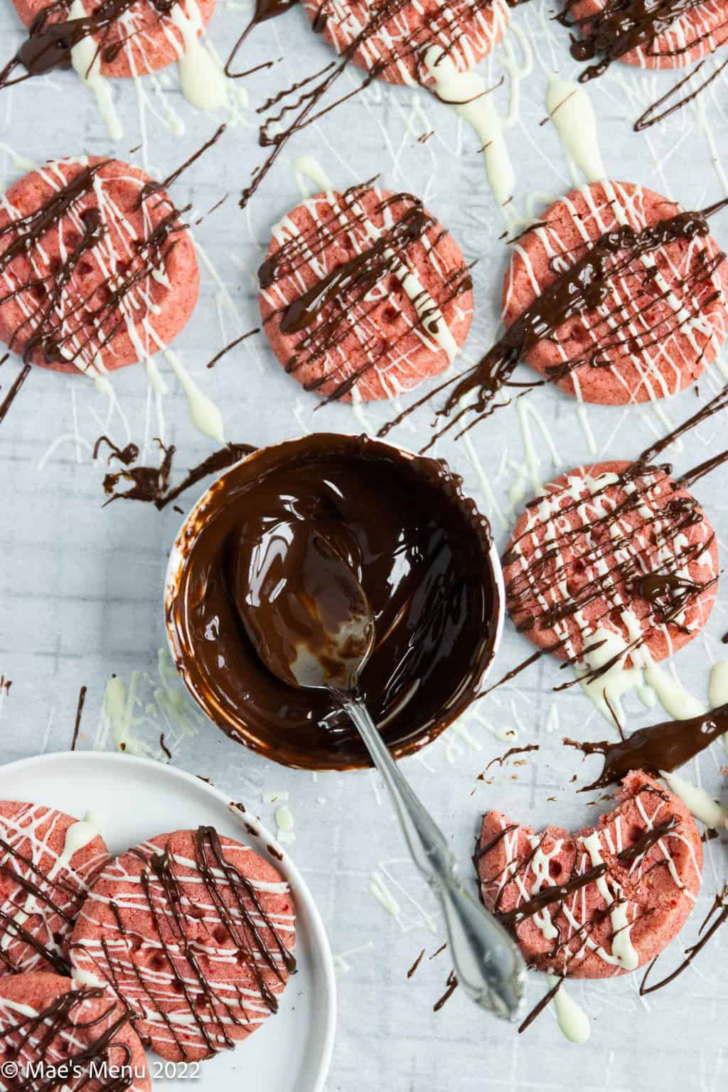Strawberry shortbread cookies around a small dish of melted chocolate.
