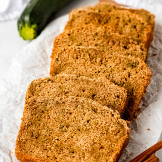 An angled shot of sliced gluten-free zucchini bread on crumbled parchment paper.