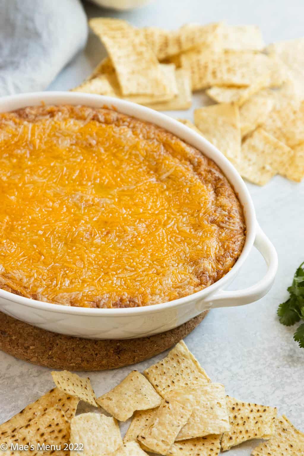 A white dish of refried bean dip with tortilla chips.