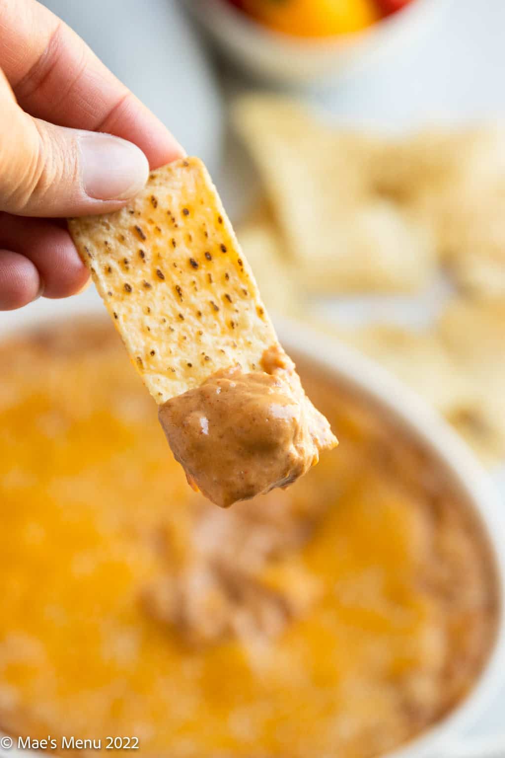 A tortilla chip with bean dip on it.