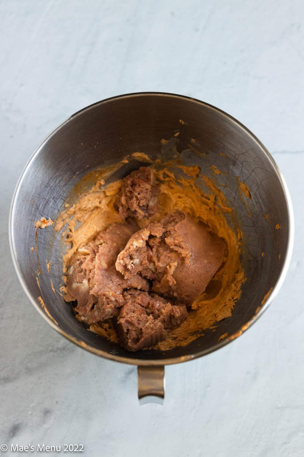 An overhead shot of a mixing bowl with taco cream cheese and refried beans.