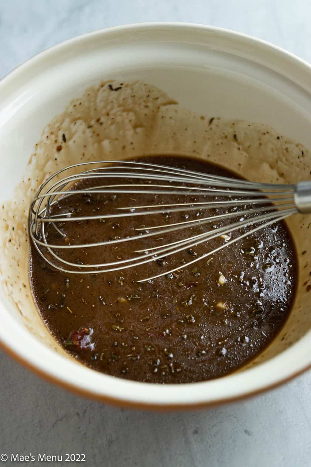 A large ceramic bowl of a whisk and balsamic dressing.