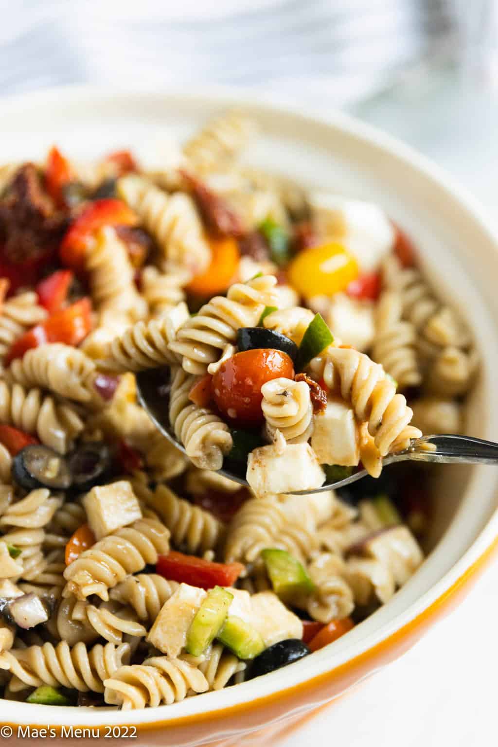 An up-close shot of a spoon taking a scoop of the pasta salad from the bowl.