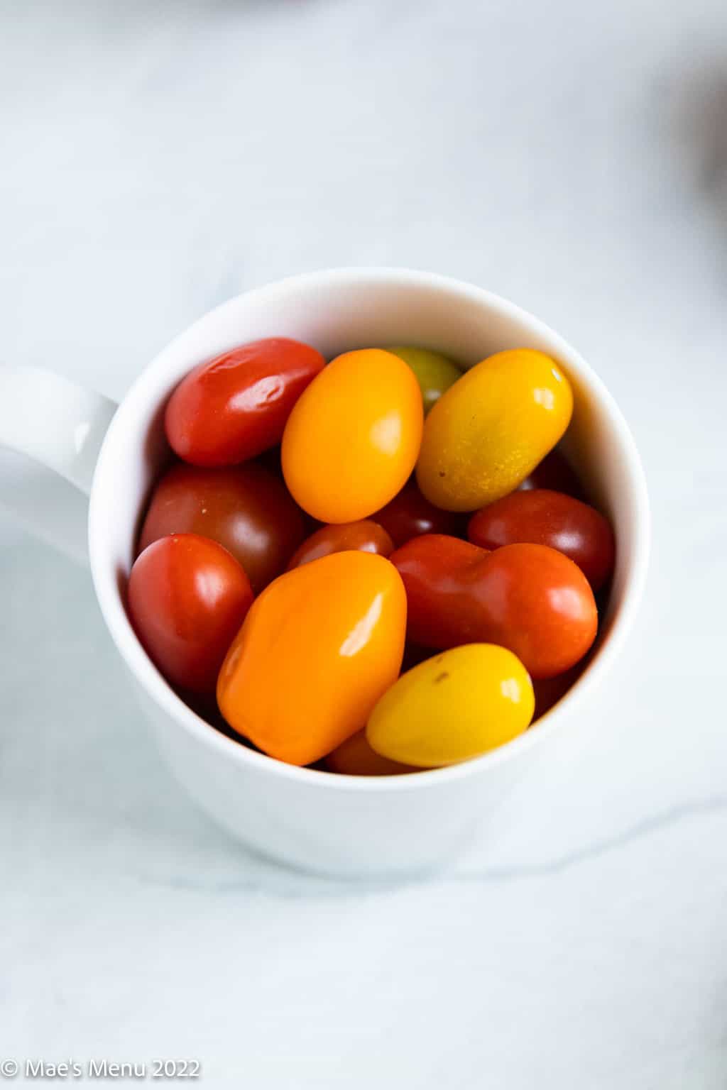 An up-close shot of cherry tomatoes in a small white cup.