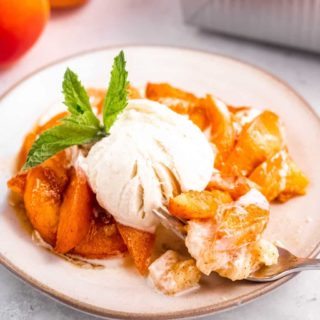 An up-close shot of a serving apricot cobbler with ice cream and mint.