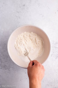 Whisking flour, sugar, and baking powder together.