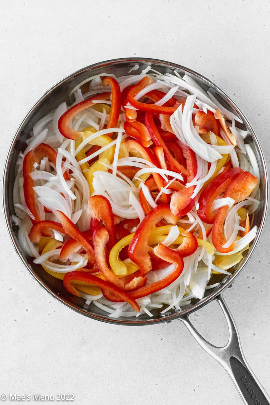 An overhead shot of a skillet of peppers and onions.