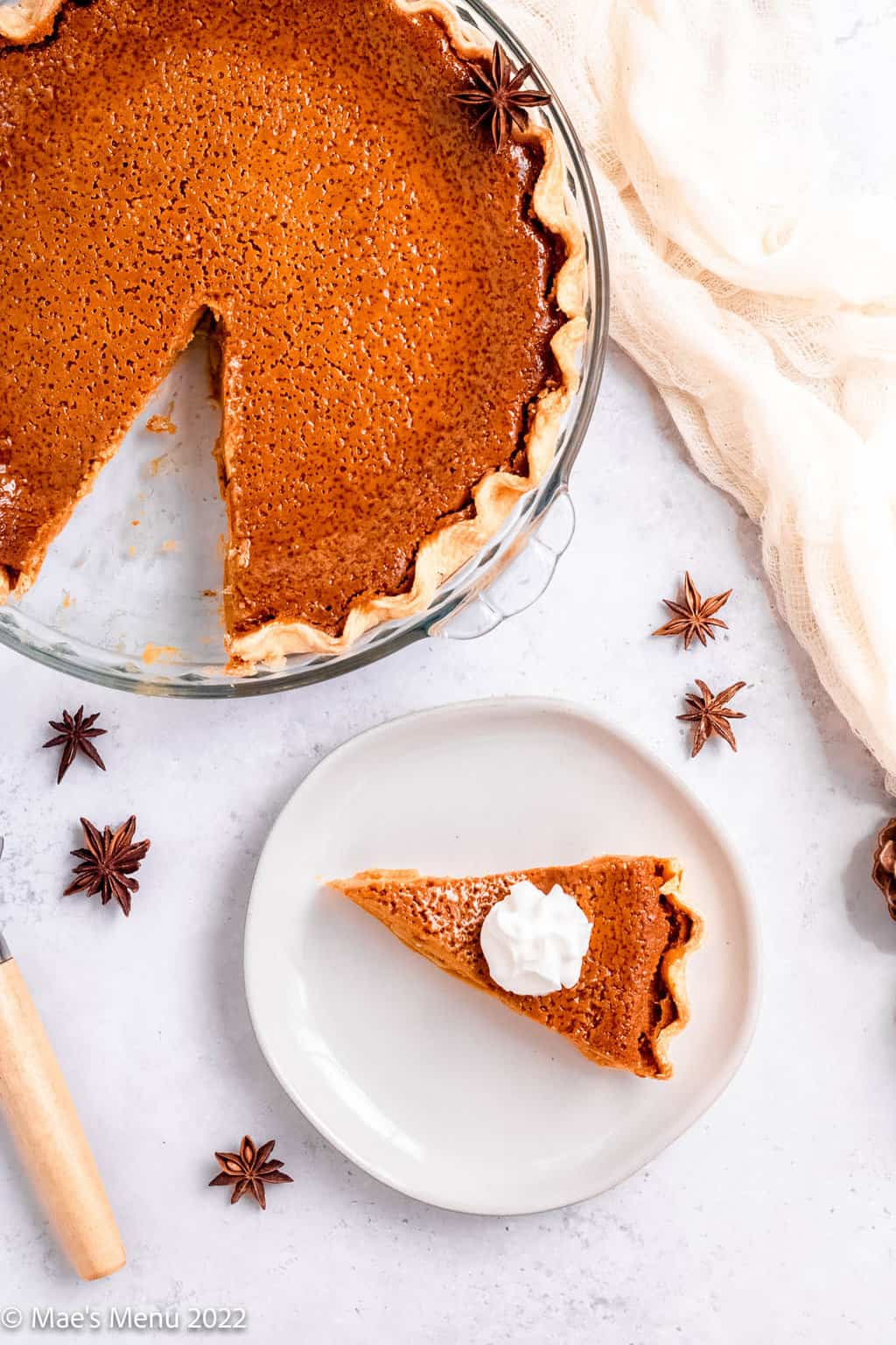 An overhead shot of a pie plate of gluten free pumpkin pie next to a small plate of pumpkin pie with whipped cream.