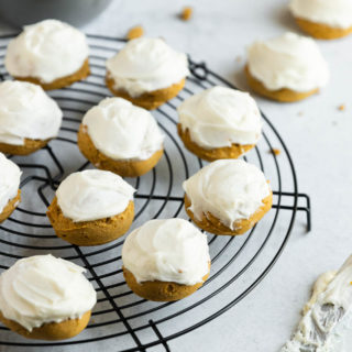 A circular cooling rack of gluten-free pumpkin cookies with cream cheese icing.