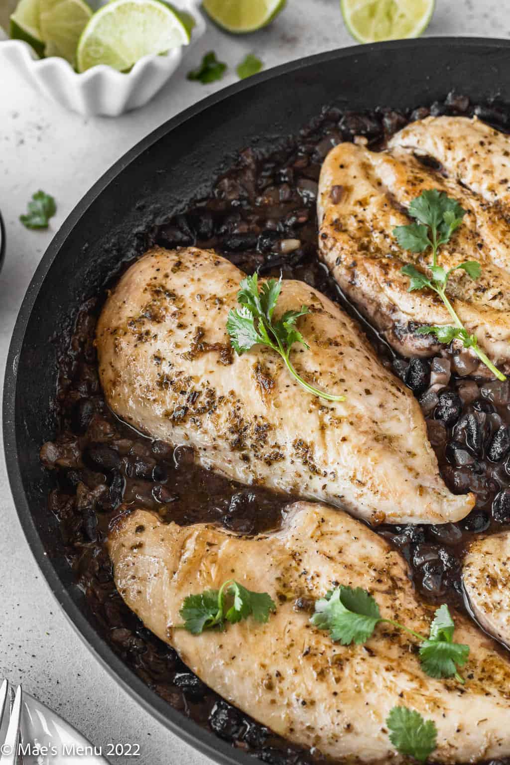 Chicken in black bean sauce in a pan with cilantro on top.