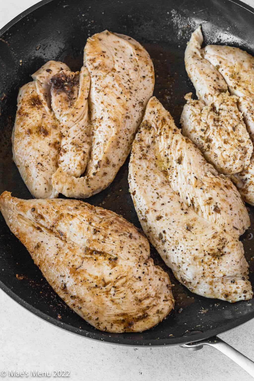 Chicken breasts sauteed in a pan.