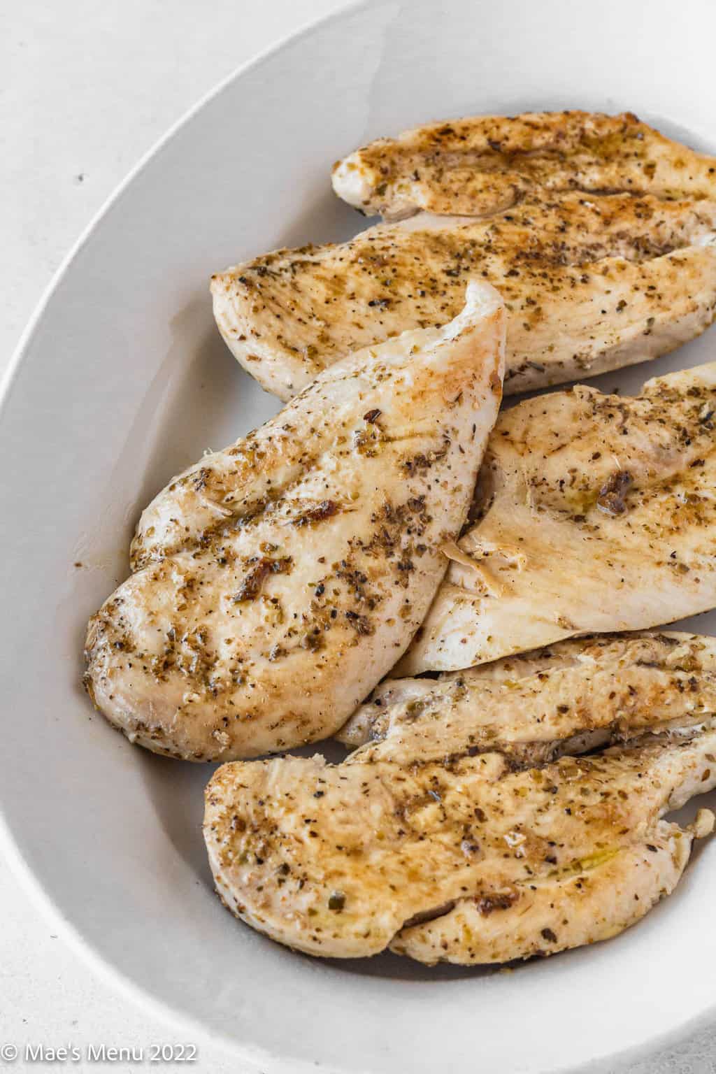Sauteed chicken breasts on a white plate.