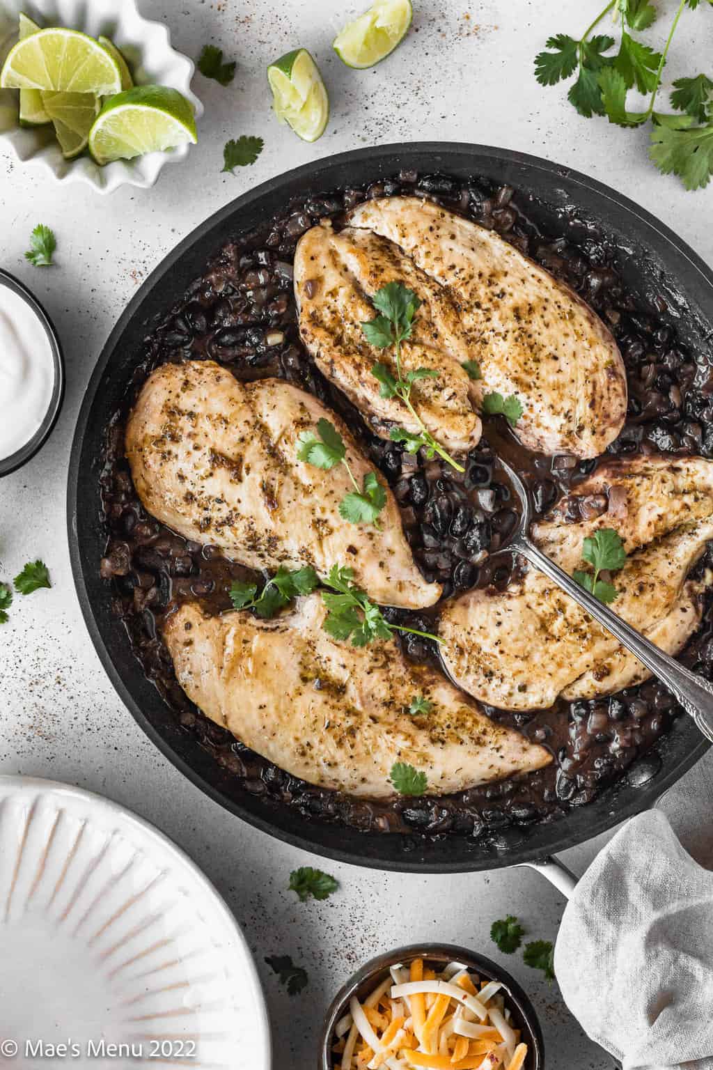 An overhead shot of a pan of southwest chicken with black bean sauce with a spoon in it.
