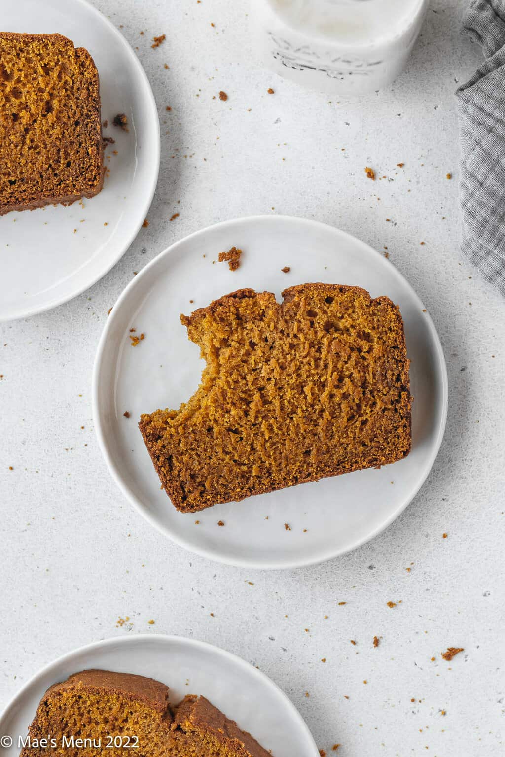 slice of gluten free pumpkin bread with a bite taken out of it on a round white plate.