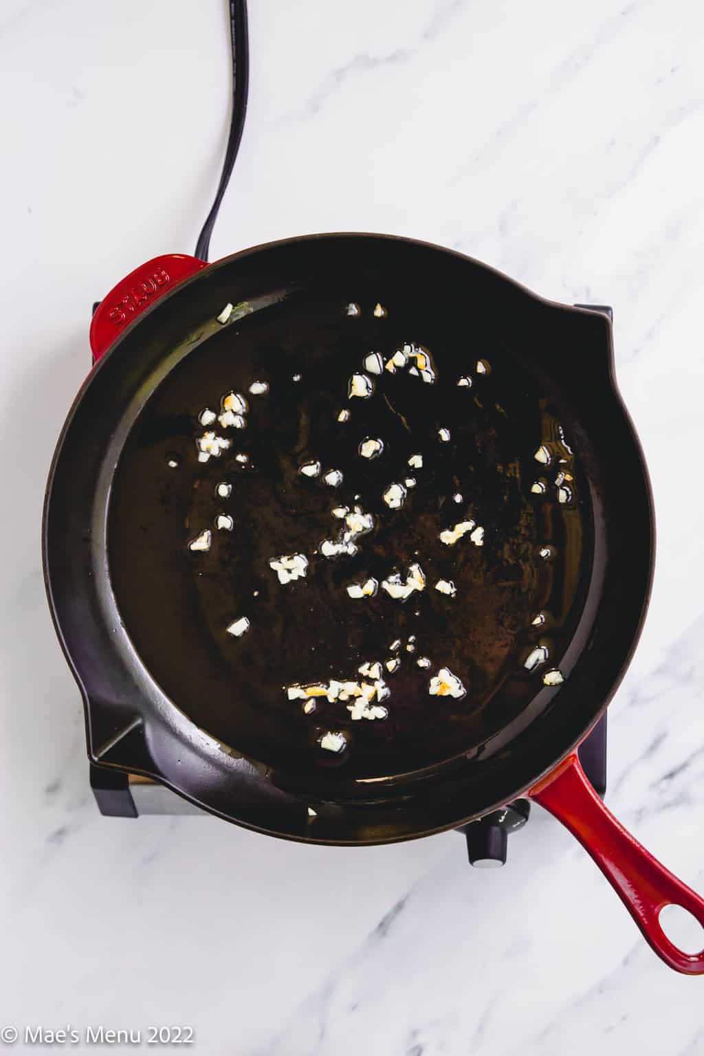 Sauteing garlic in a large red skillet.