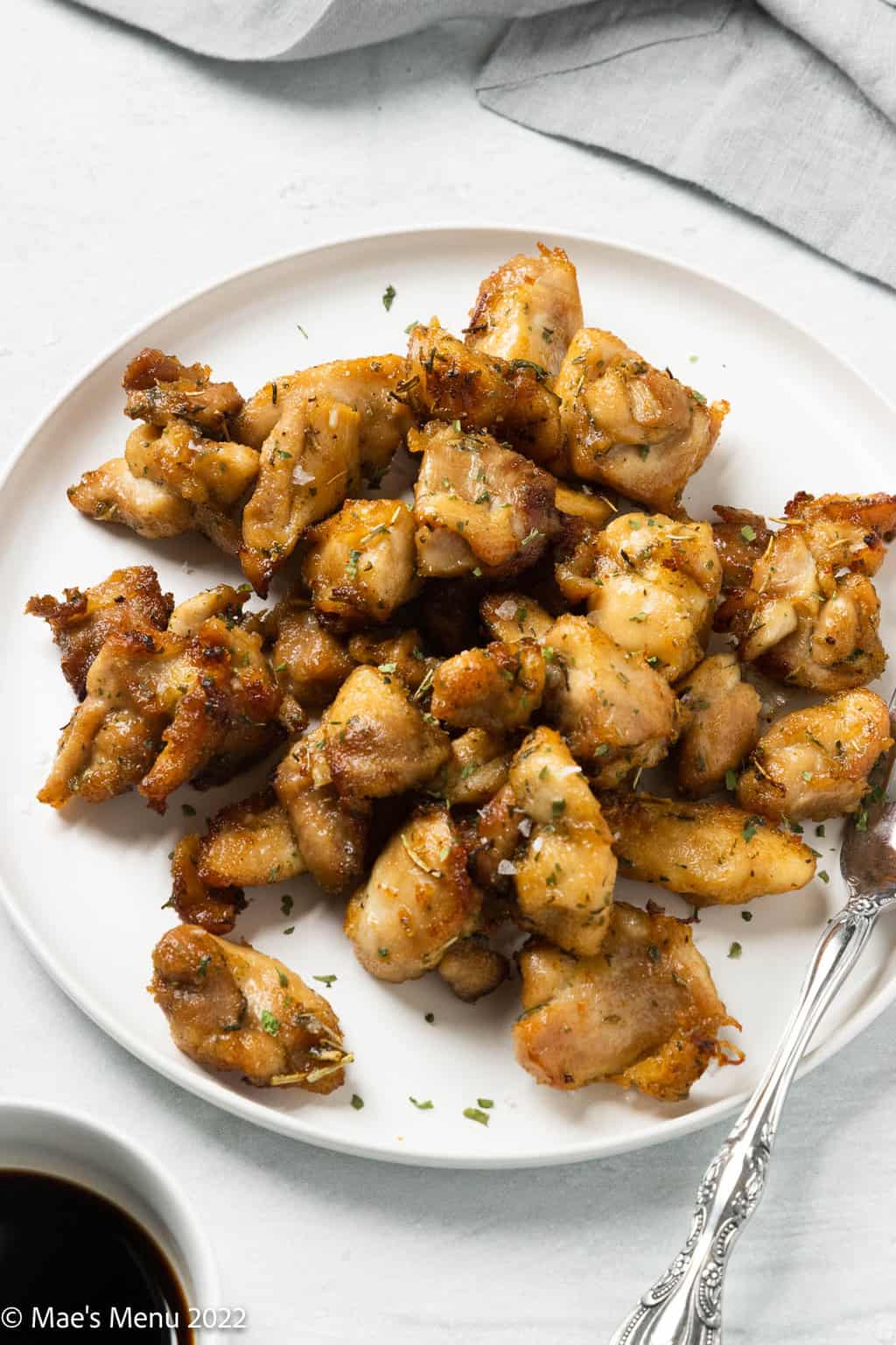 A white plate of air fryer chicken bites with a fork.