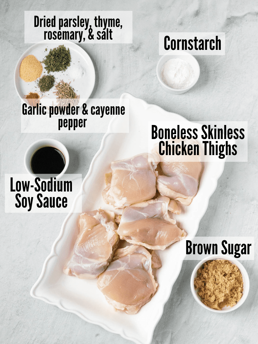All of the ingredients for air fryer chicken bites: boneless skinless chicken thighs, cornstarch, brown sugar, low-sodium soy suace, garlic powder, cayenne pepper, dried parsley, thyme, rosemary, and salt.