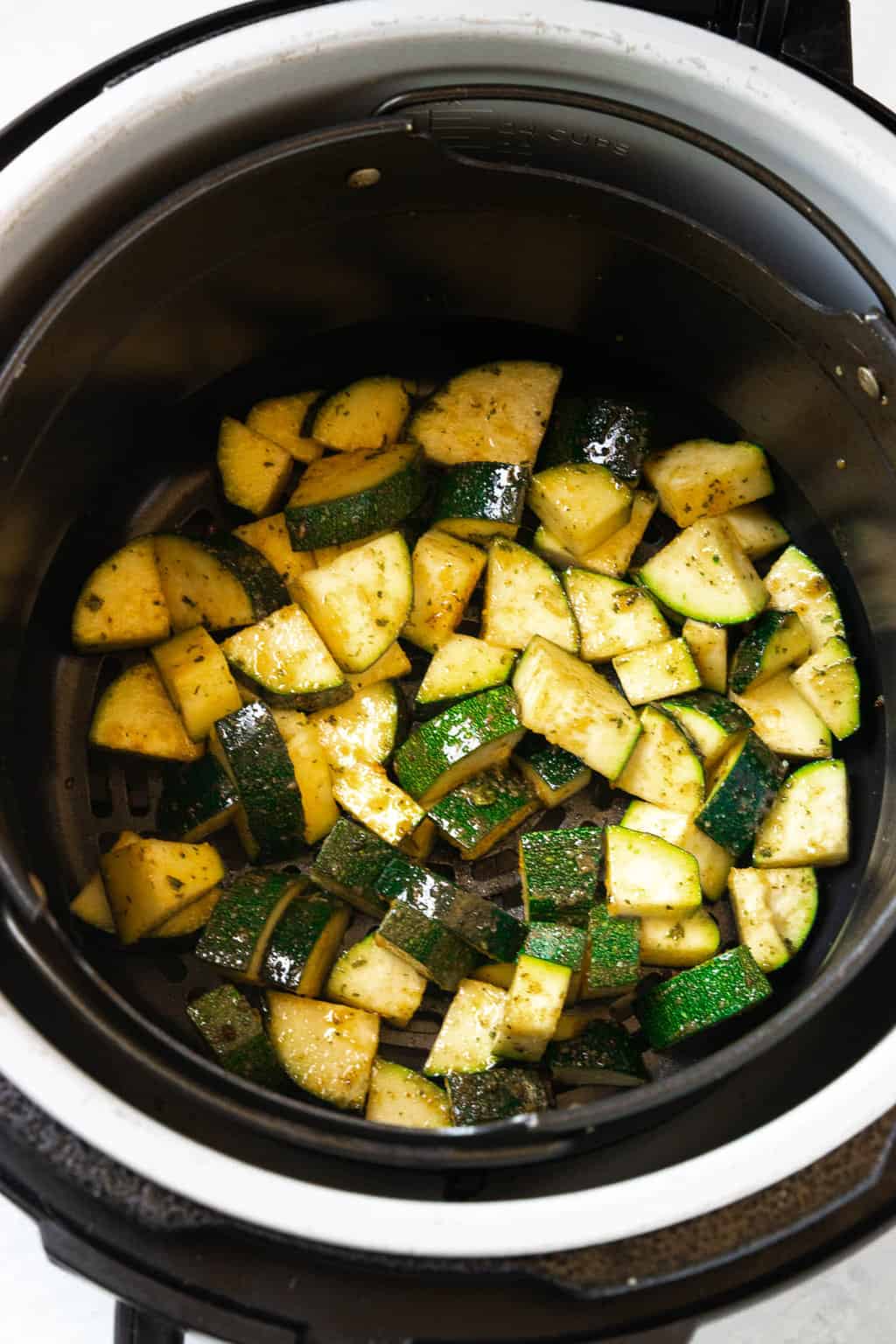 A air fryer basket of zucchini with spices.