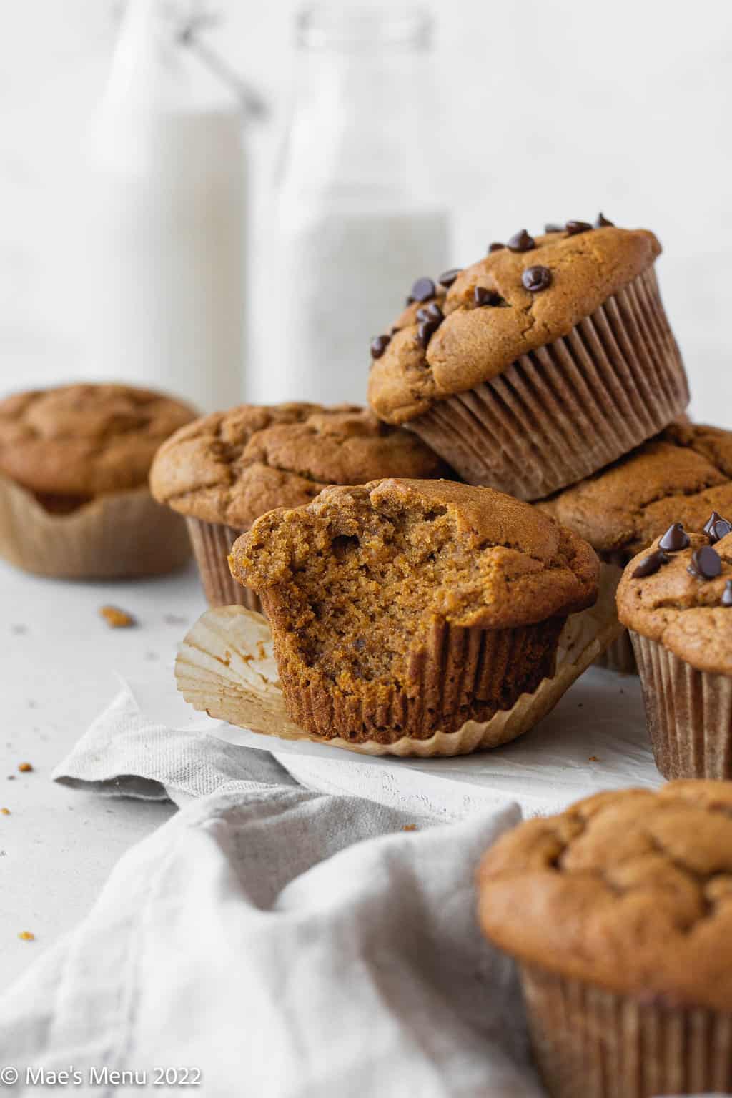 A stack of banana pumpkin muffins; one of them has a large bite taken out of it.