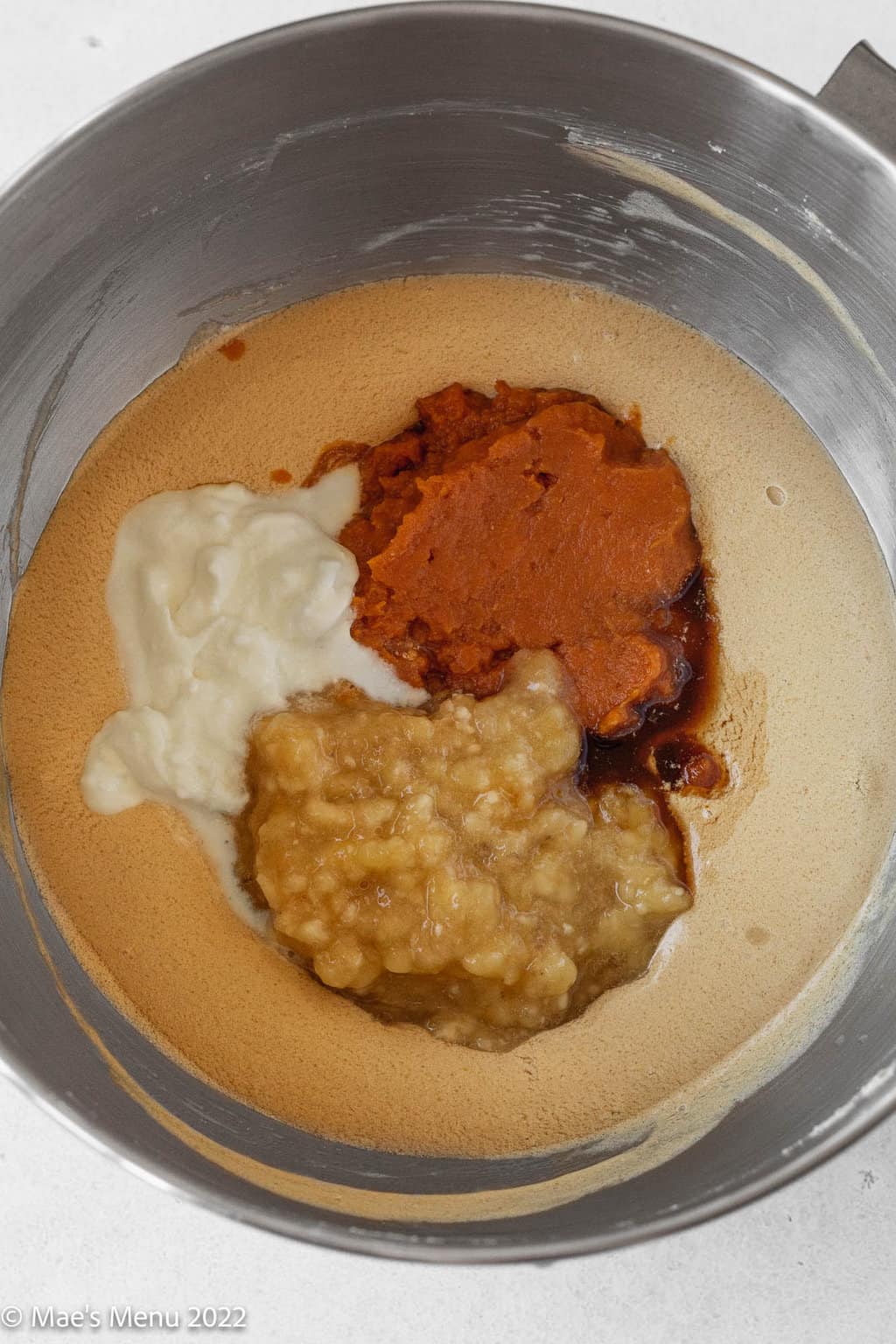 Adding the Greek yogurt, pumpkin puree, and mashed bananas to the creamed butter and sugar mixture.