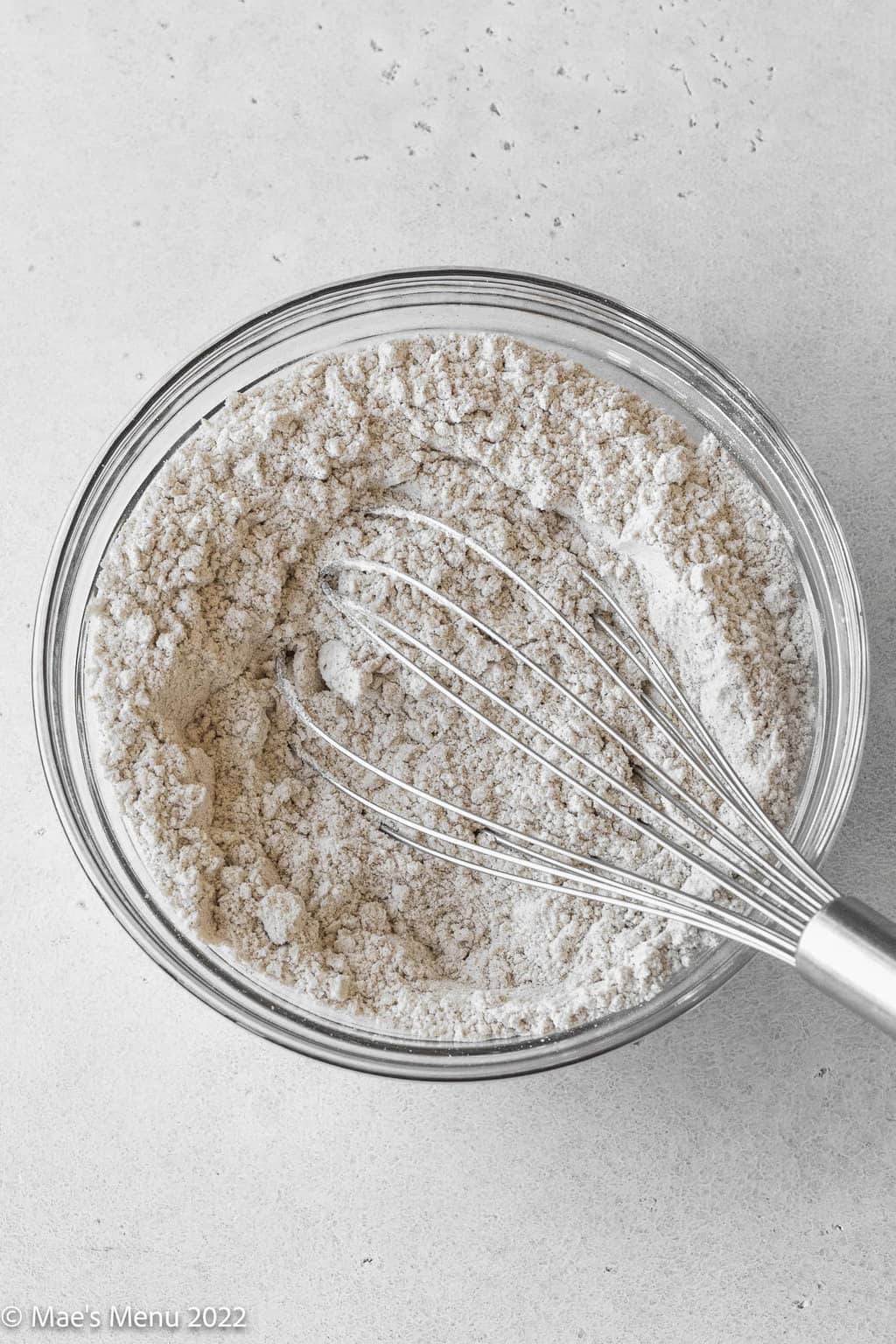 A whisking bowl of flour and seasonings with a whisk.