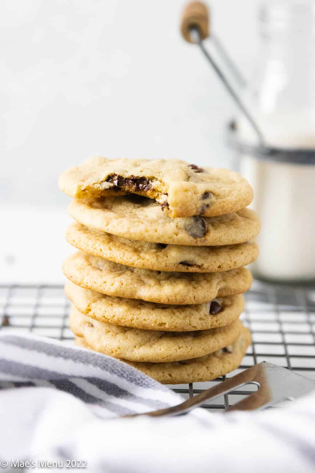 A stack of dairy free chocolate chip cookies with a bite taken out of the top one.