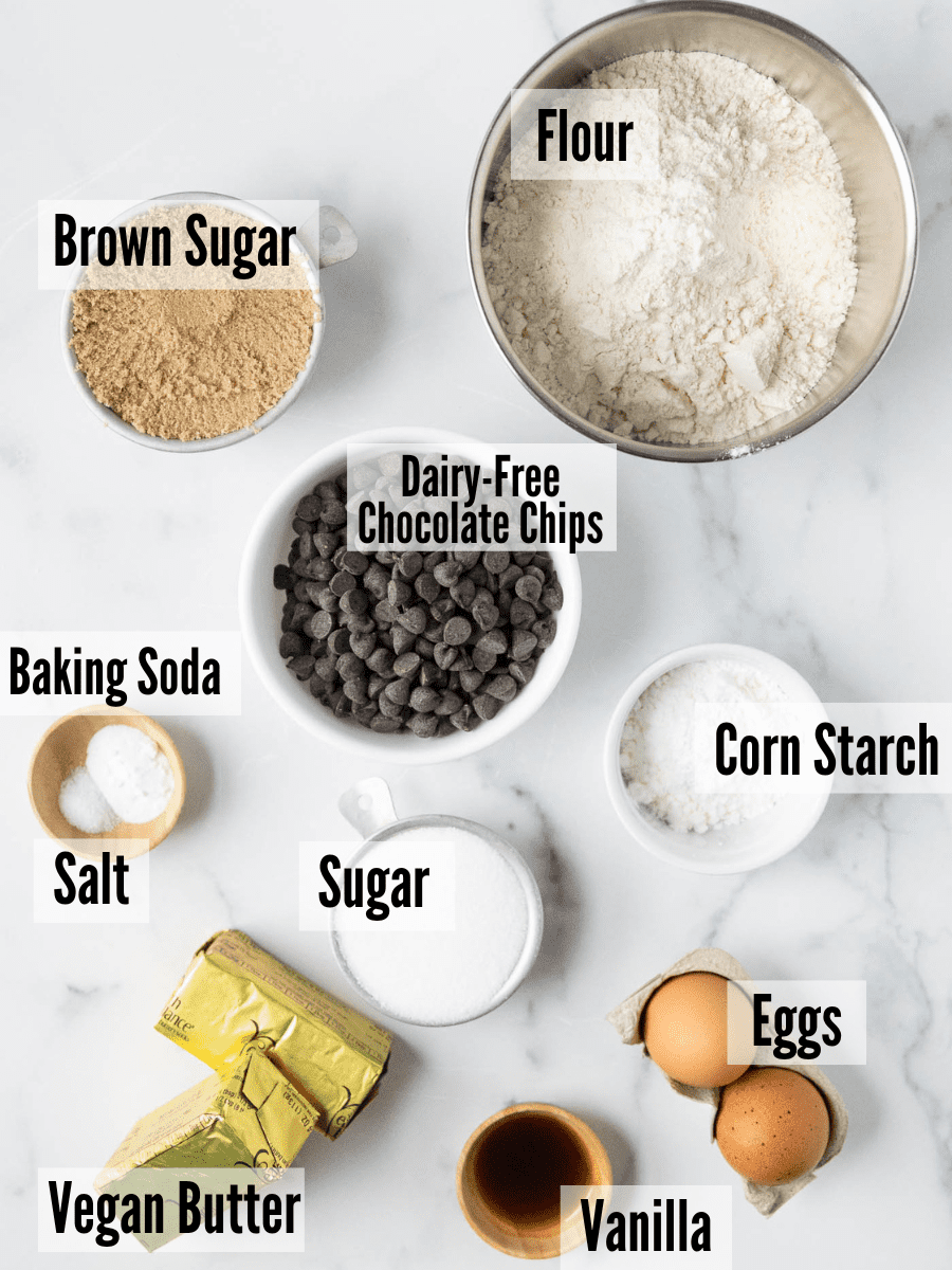 All of the ingredients for the dairy free chocolate chip cookies: flour, brown sugar, chocolate chips, corn starch, baking soda, salt, sugar, eggs, vanilla, and vegan butter.