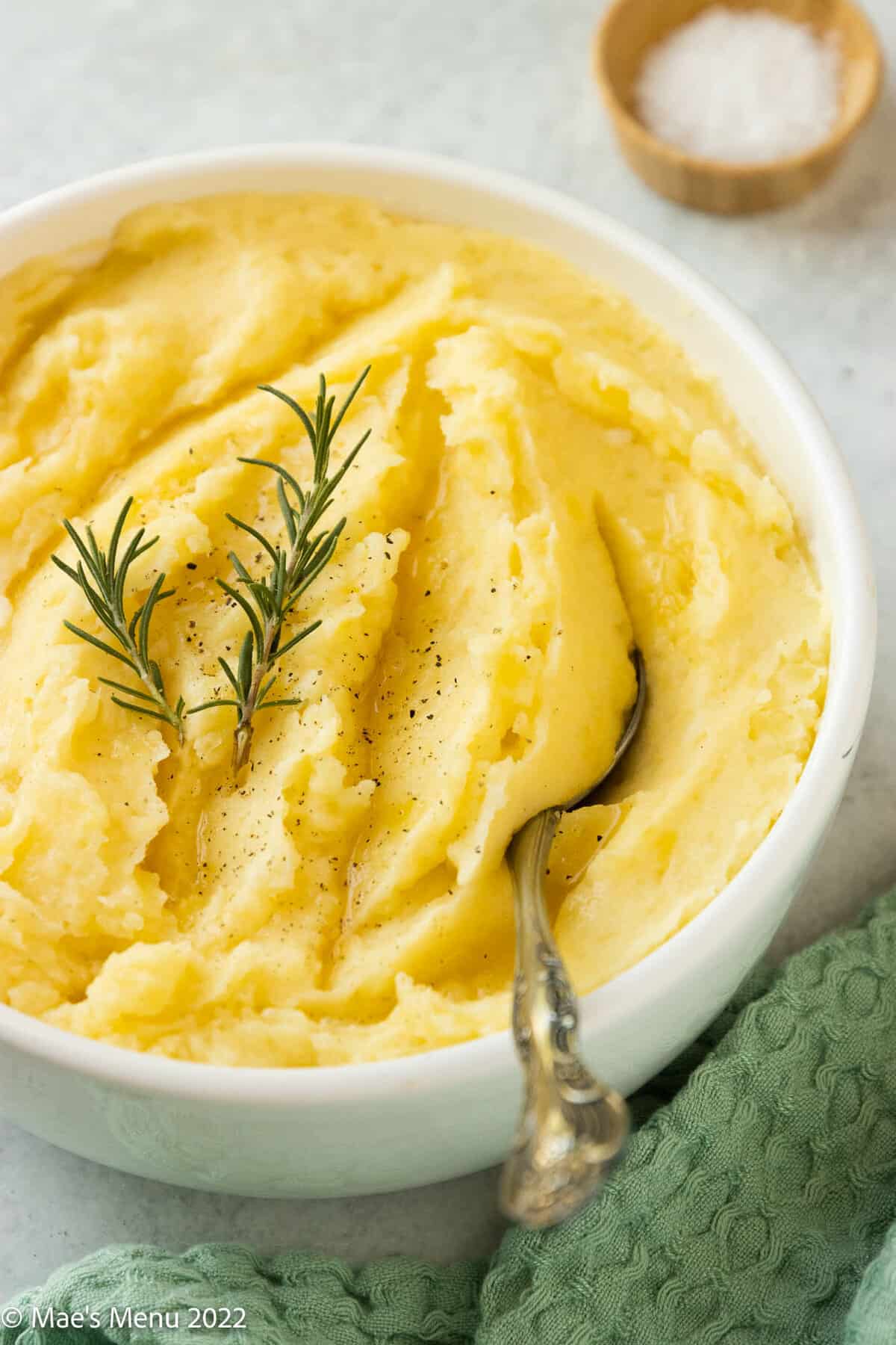 A white bowl of dairy-free mashed potatoes with a serving spoon in it.