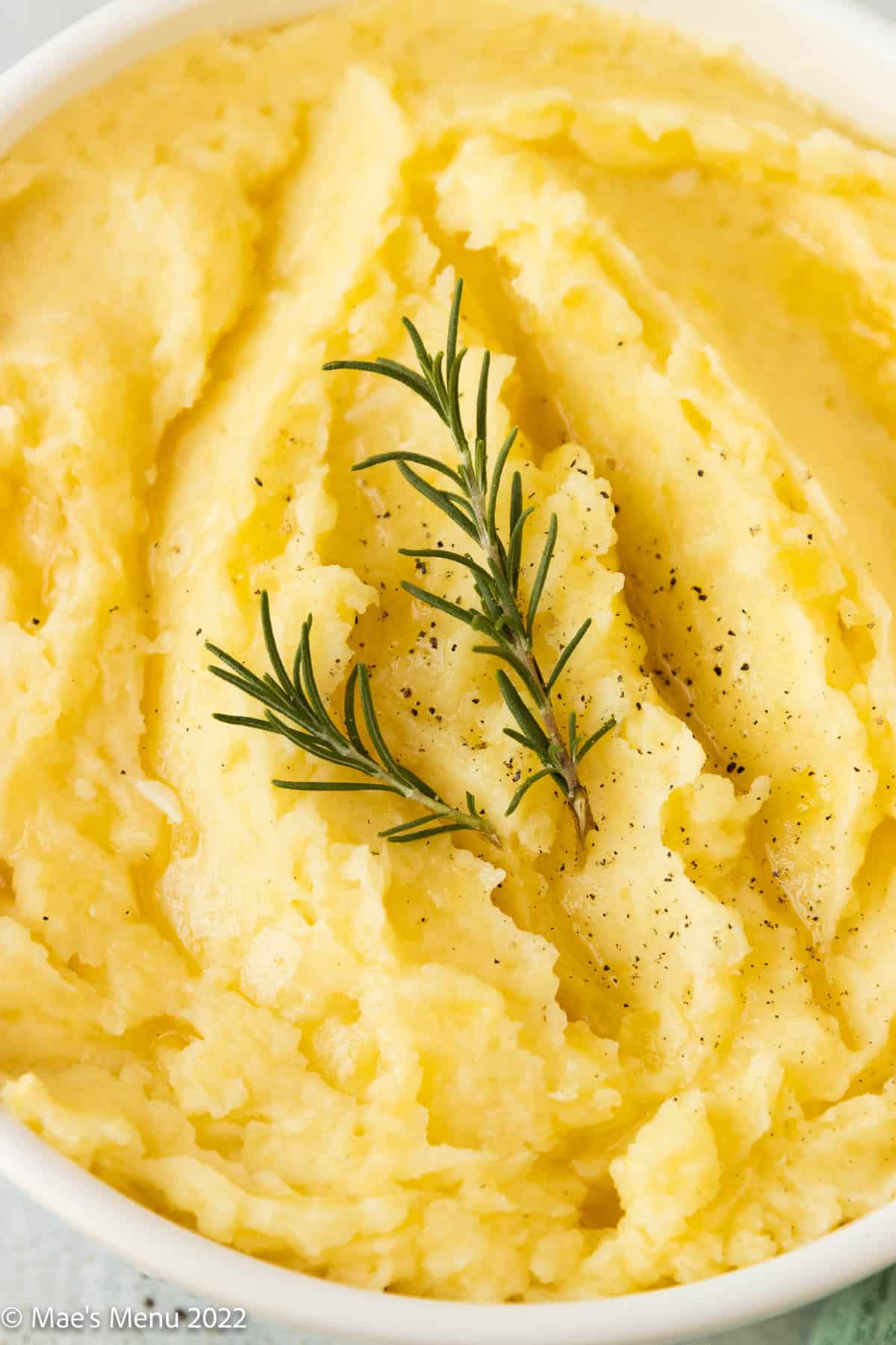 An up-close shot of dairy-free mashed potatoes with two sprigs of rosemary on top.