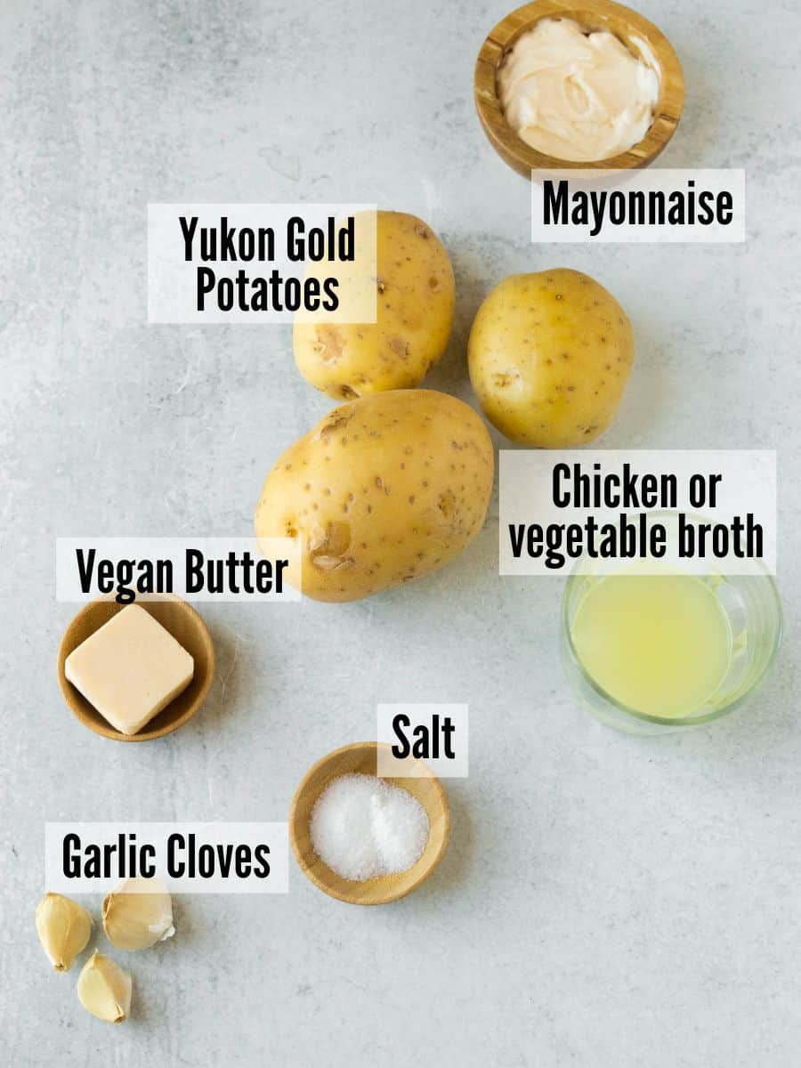 All of the ingredients for dairy free mashed potatoes: mayo, potatoes, broth, salt, butter, and garlic.
