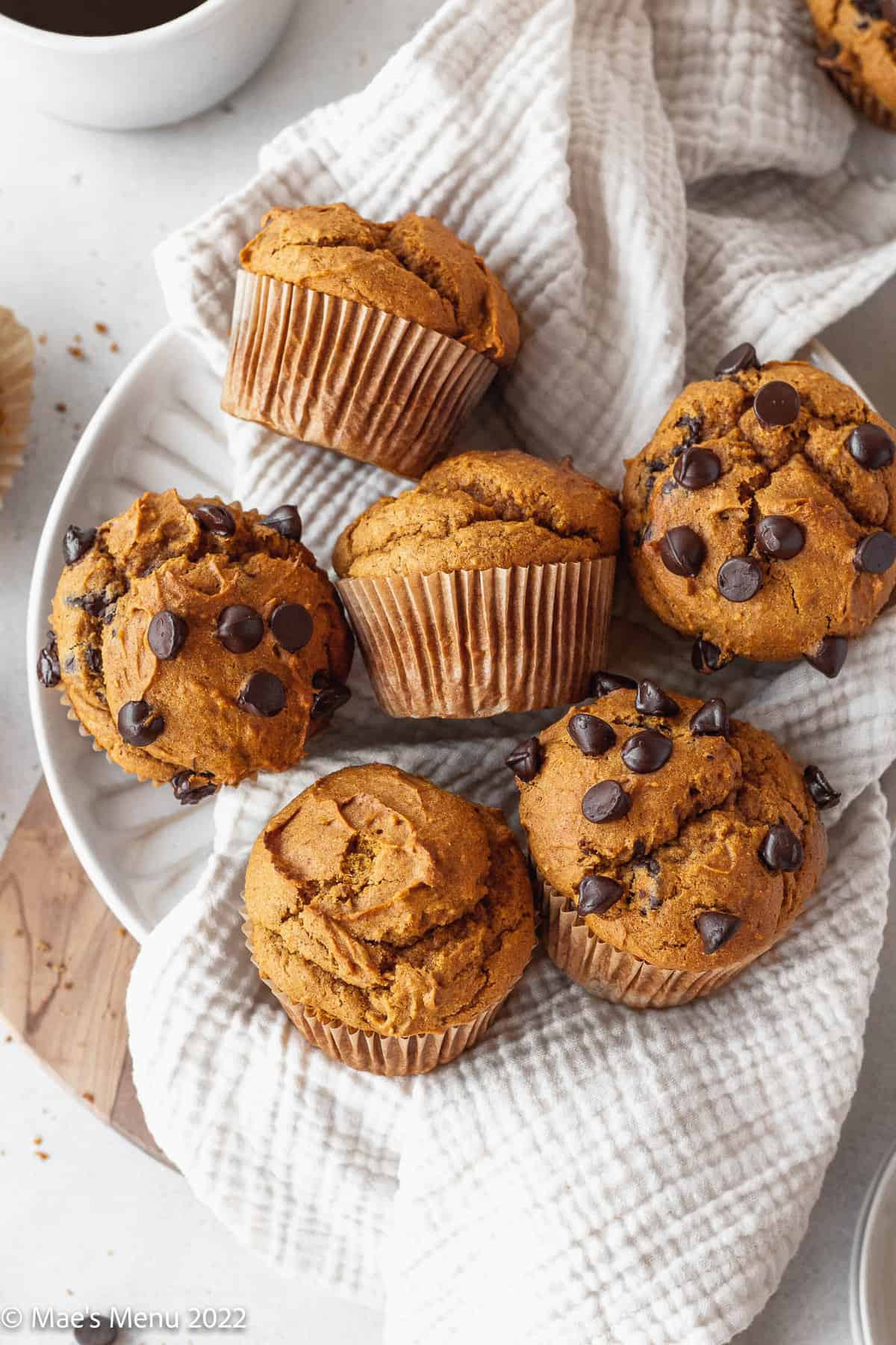 Gluten-free pumpkin muffins laying on a towel in a white bowl.