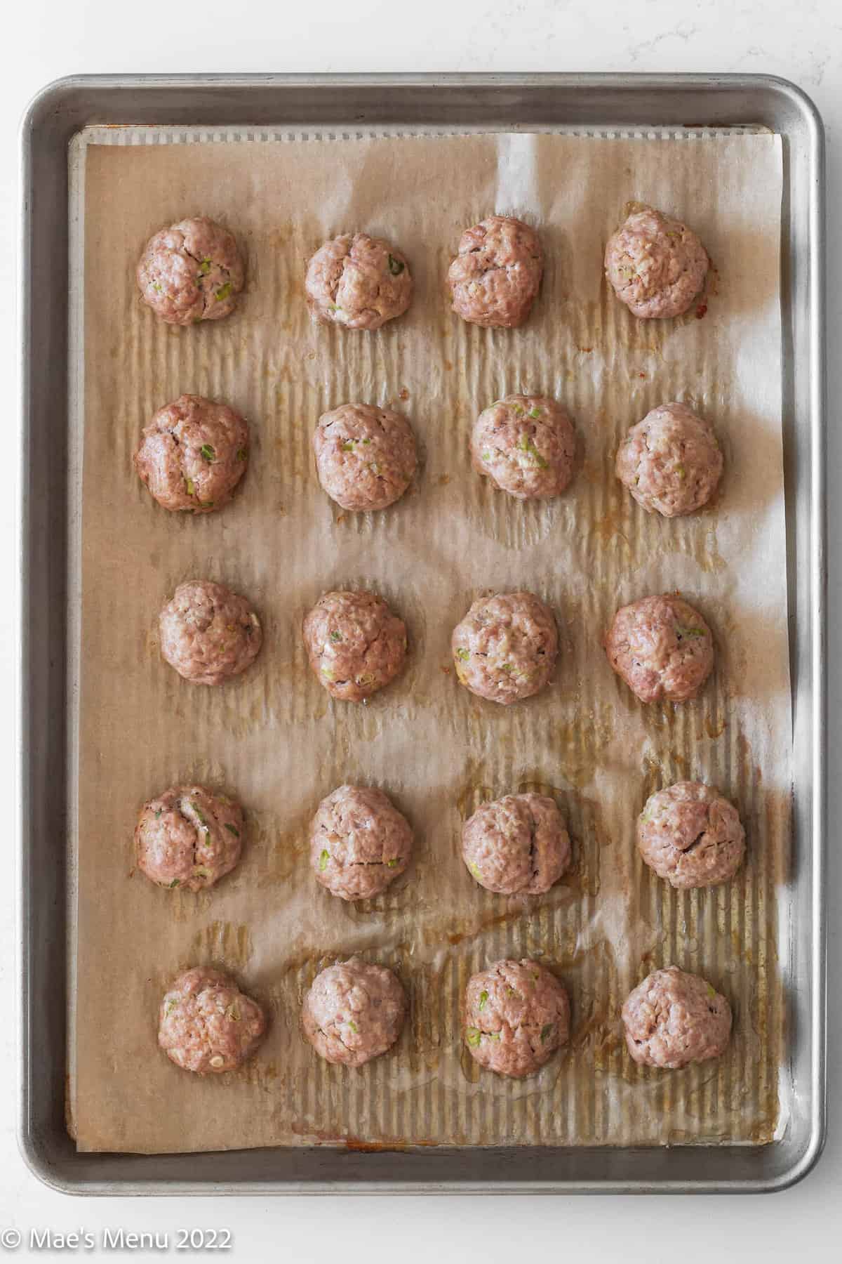 baked asian pork meatballs on a parchment lined sheet tray.
