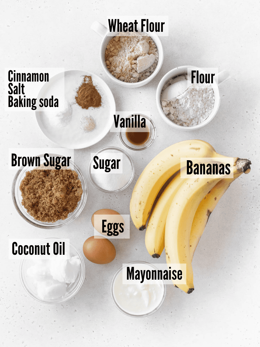 All of the ingredients for dairy free banana bread: bananas, wheat flour, all purpose flour, vanilla, sugar, brown sugar, eggs, bananas, mayo, coconut oil, eggs, and seasonings.