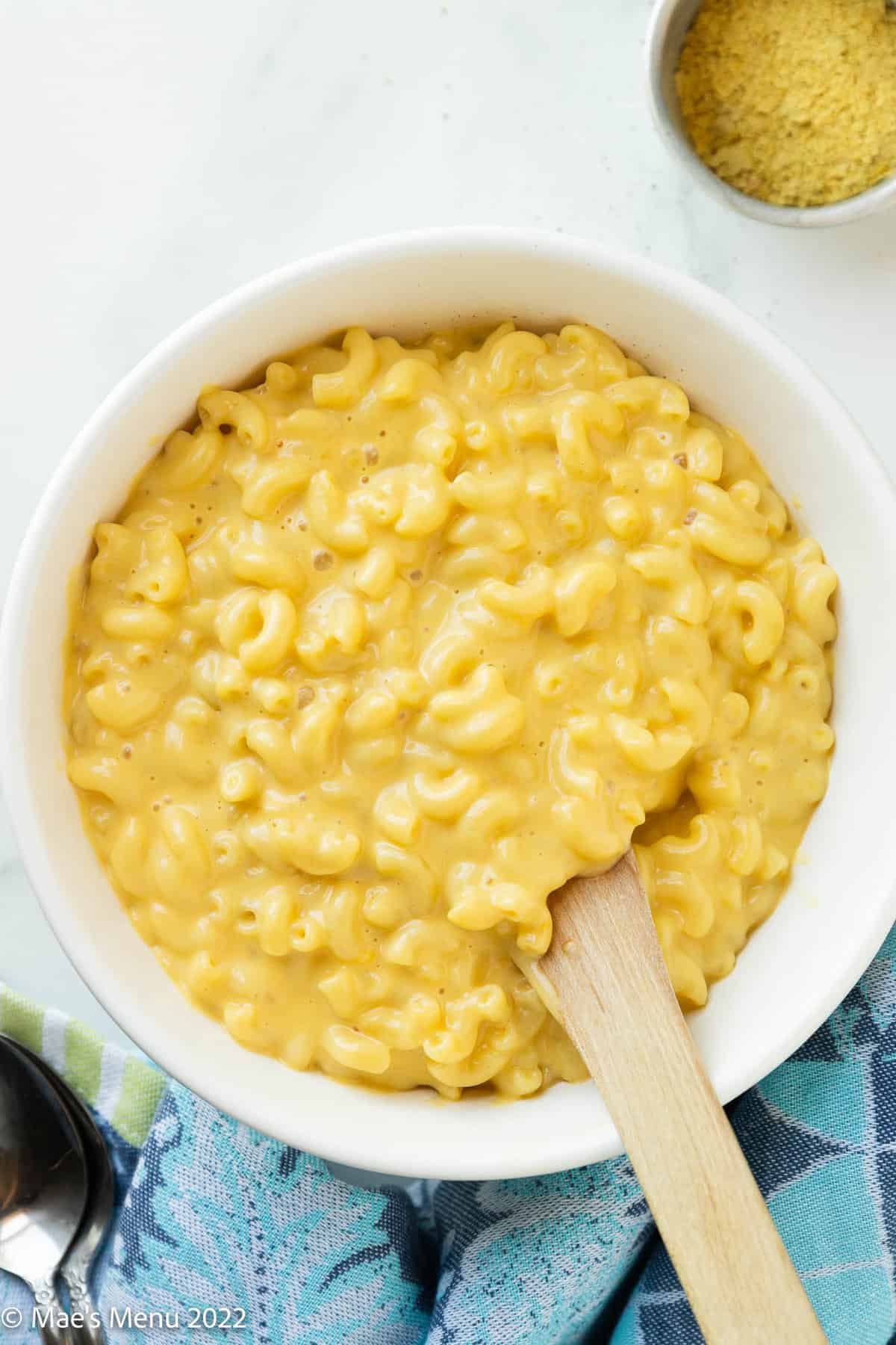 white serving bowl of lactose free mac and cheese with a wooden spoon.